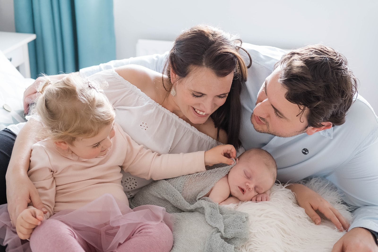 Family with a newborn baby cuddling on the bed