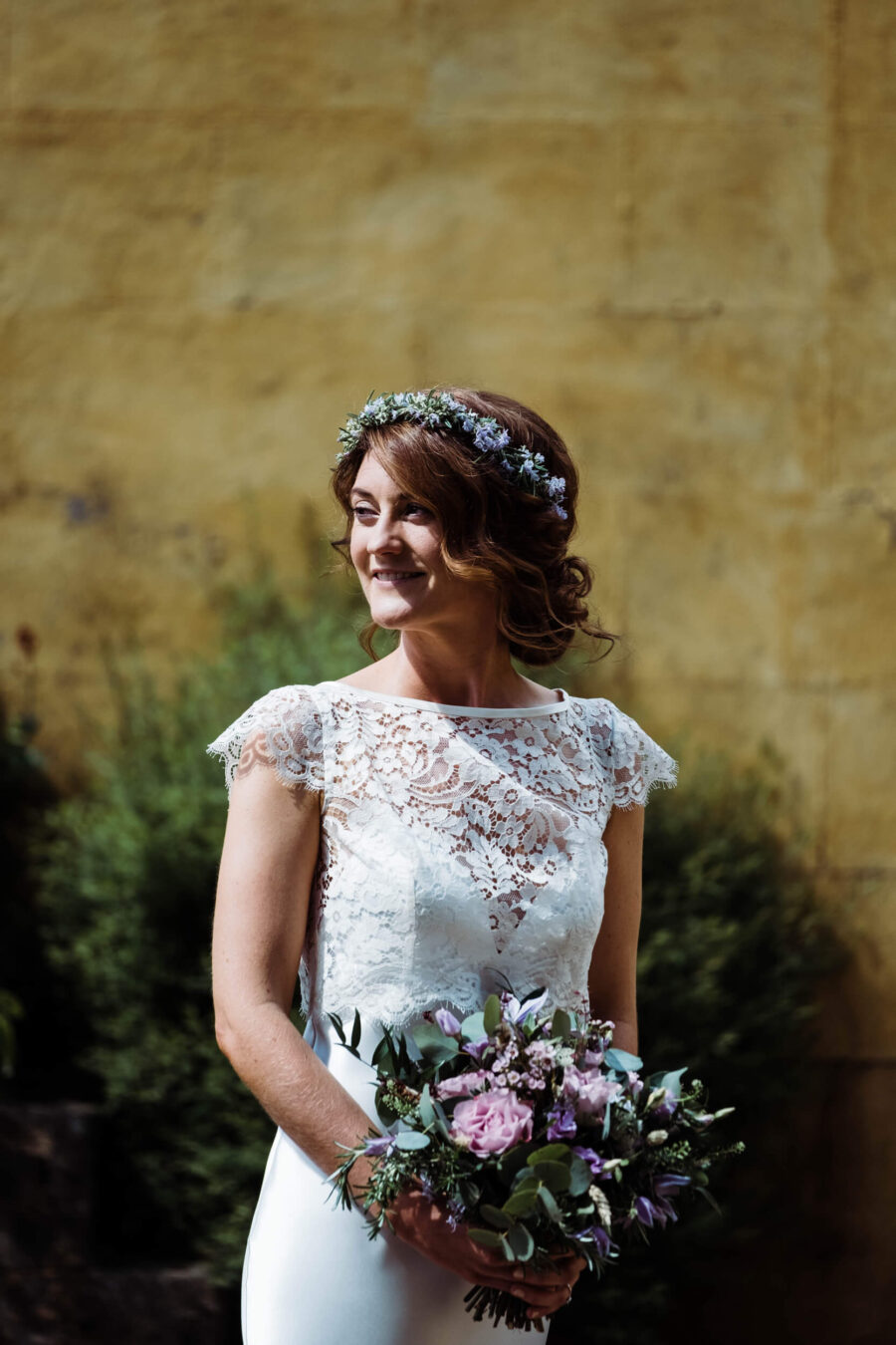 Bride in the yellow courtyard, looking away and smiling at Roundwood House