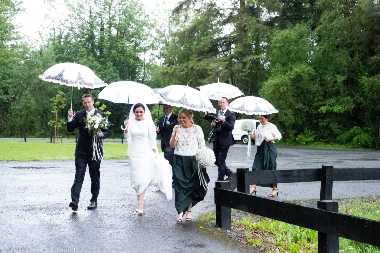 Bride party walking in the rain at Kilronan Castle lake