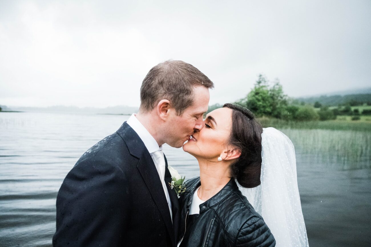 Bride and groom kissing in the rain at Kilronan Castle jetty