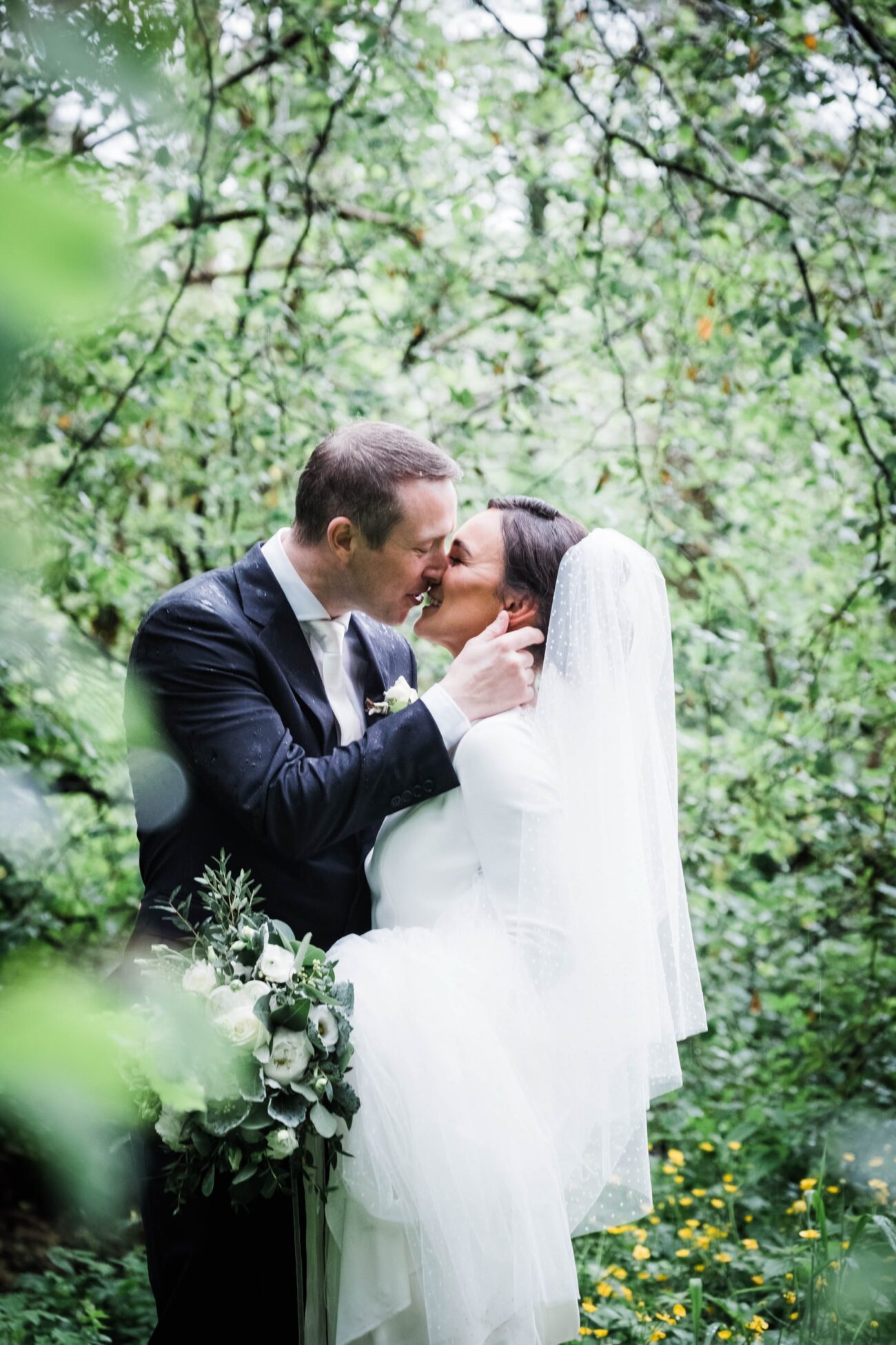 Bride and groom standing kissing in the forrest at Kilronan Castle forrest
