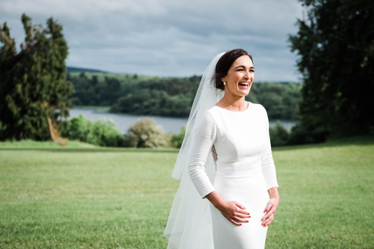 bride standing alone and laughing  in the gardens on Kilronan Castle