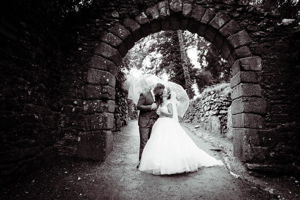 Bride and groom kissing under the umbrella at Glendalough Hotel, Wicklow