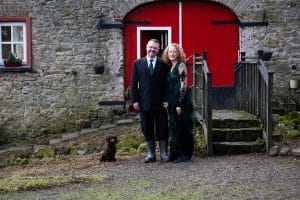 Couple standing outside barn of Roundwood House