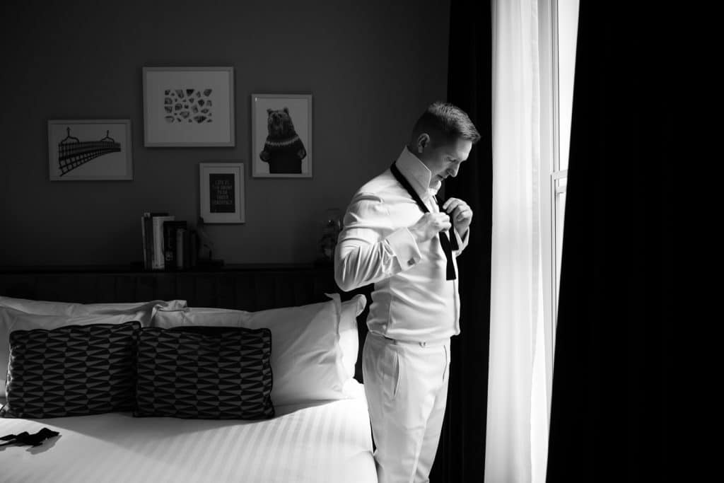 Groom standing by the winder getting ready at The Wilder Hotel