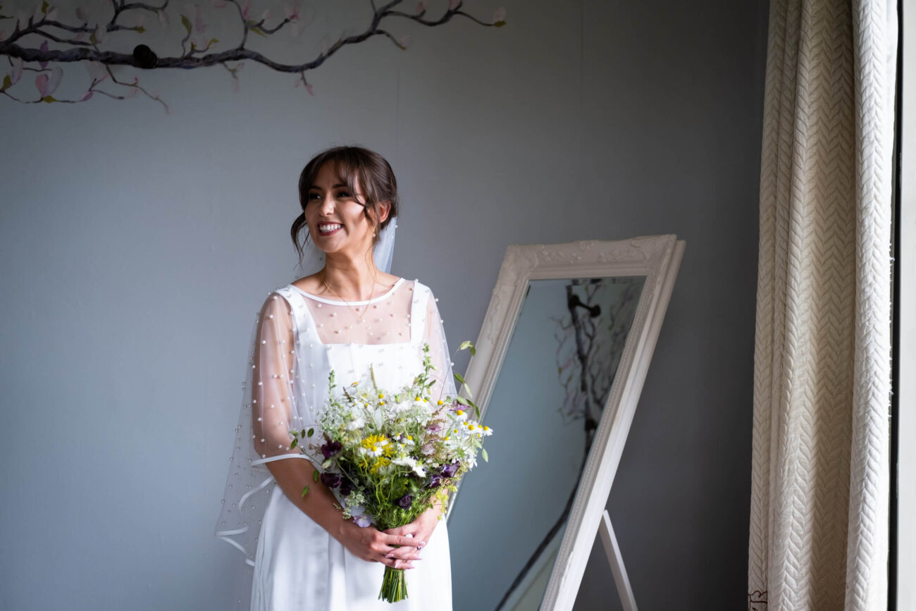 Bride with flowers in her dress in the bridal prep room at Ballintubbert Gardens and House