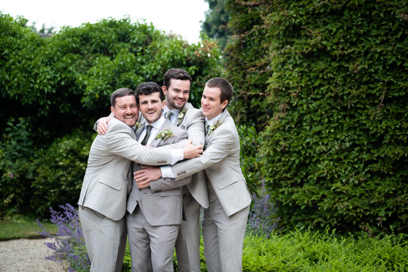 groomsmen hugging and laughing at the front of the house in Ballintubbert Gardens and House