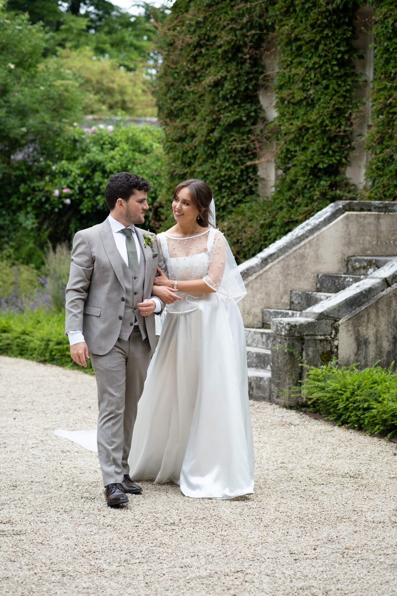 Bride and groom walking arm in arm chatting at the front of the house at Ballintubbert Gardens and House