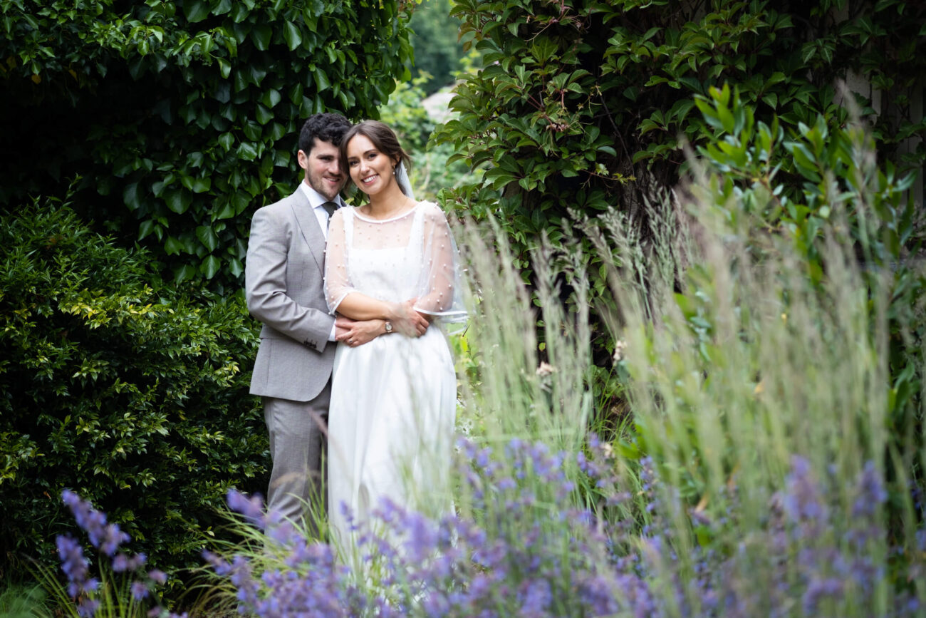 Bride and groom arm in arm facing the camera in the courtyard of Ballintubbert Gardens and House
