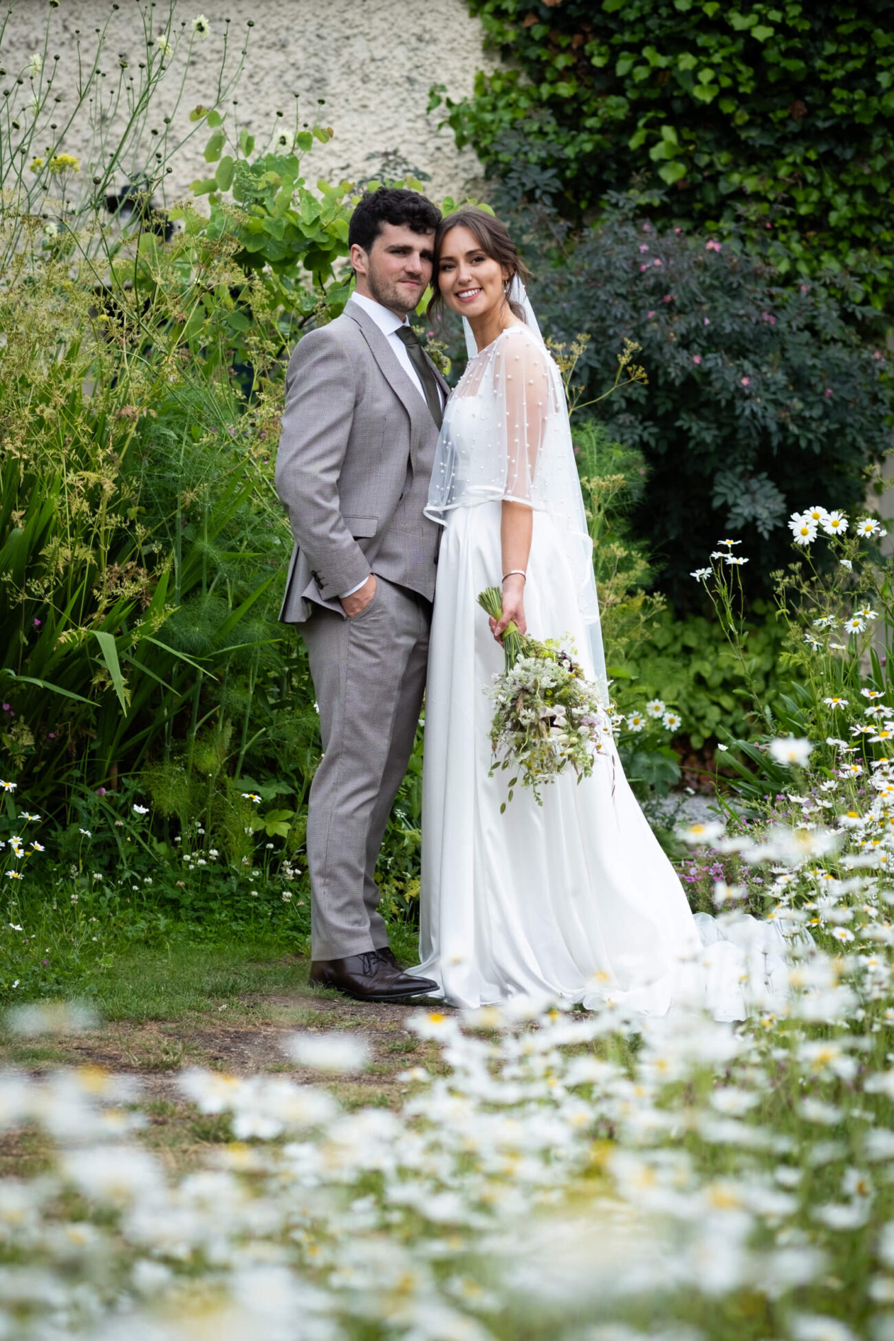 bride and groom posing, heads together and smiling in the flower garden of Ballintubbert 