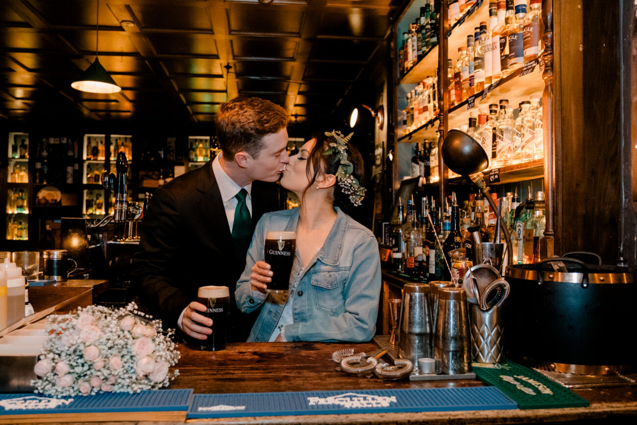couple kissing with a pint behind the bar in Dublin. 