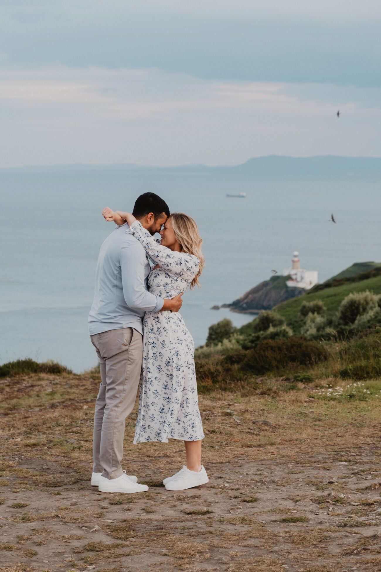 couple embracing in front of light house view at Howth Head