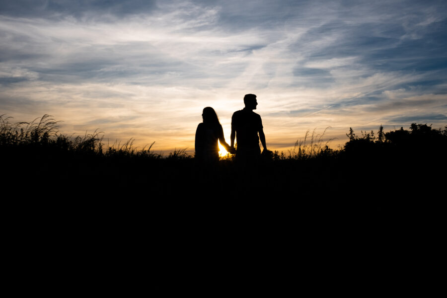 silhouette of couple holding hands against a golden sunset on Howth Summit for an engagement photoshoot in Howth Summit