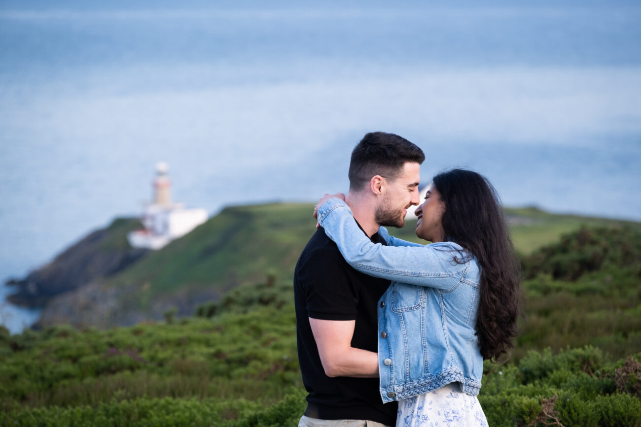 couple hugging at Howth Summit with the lighthouse in the background