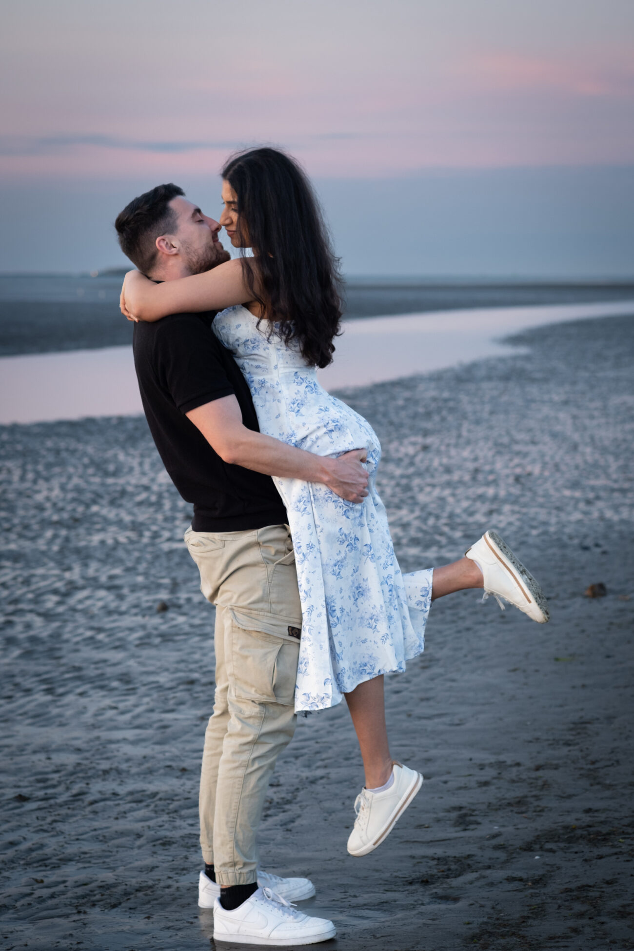 man lifting his girlfriend romantically on the beach in Burrow Beach