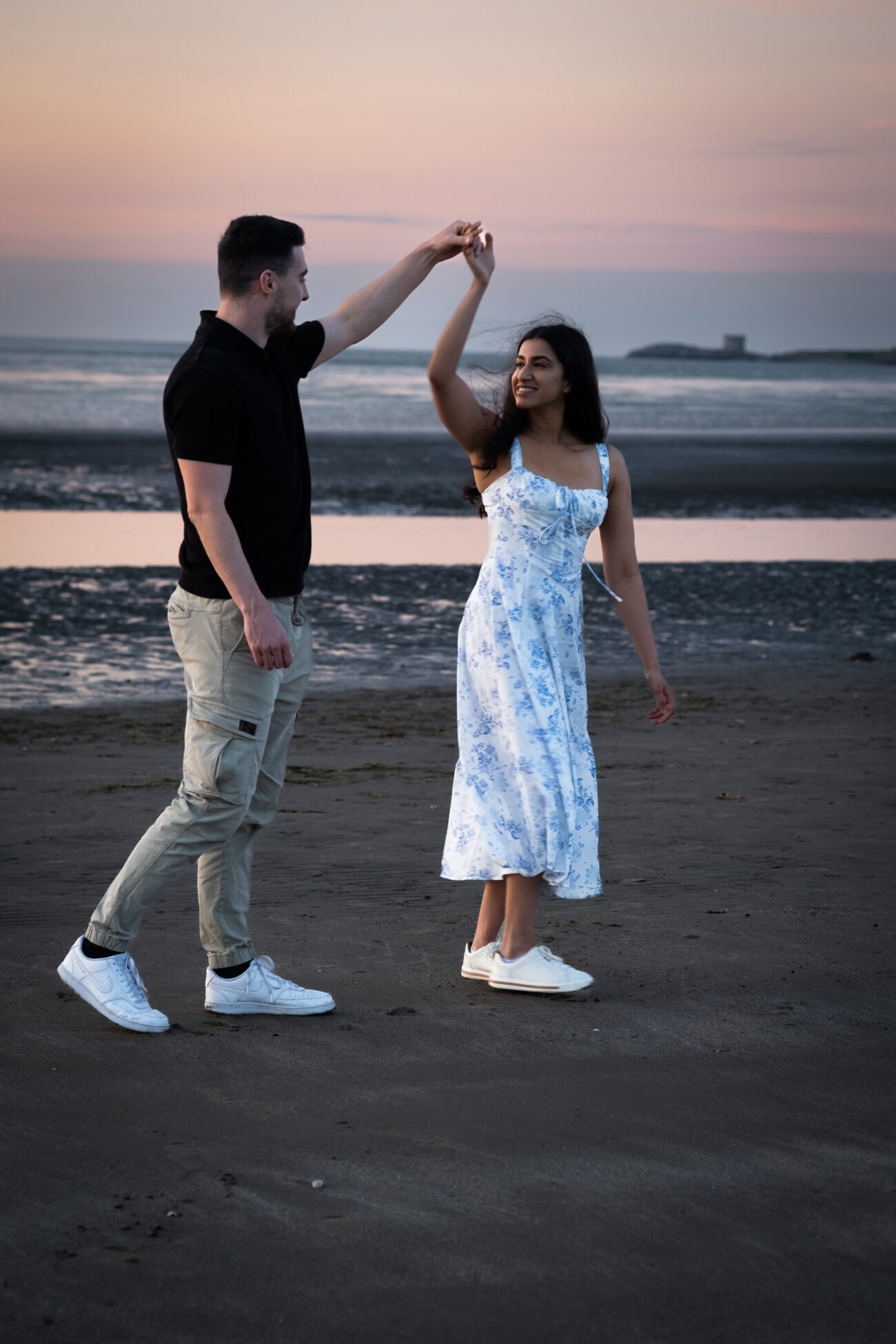 couple holding hands and walking on the beach in Burrow Beach Howth