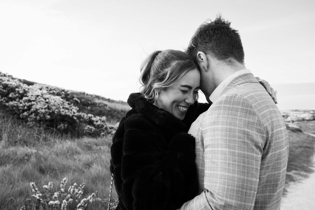 Howth Head engagement shoot, a secret proposal at Howth Head, couple embracing and laughing