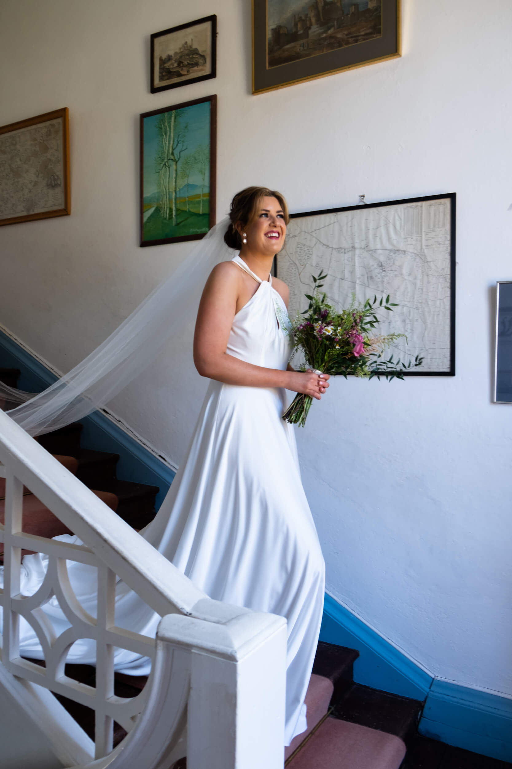 Bride walking down the stairs with flowers at Roundwood House