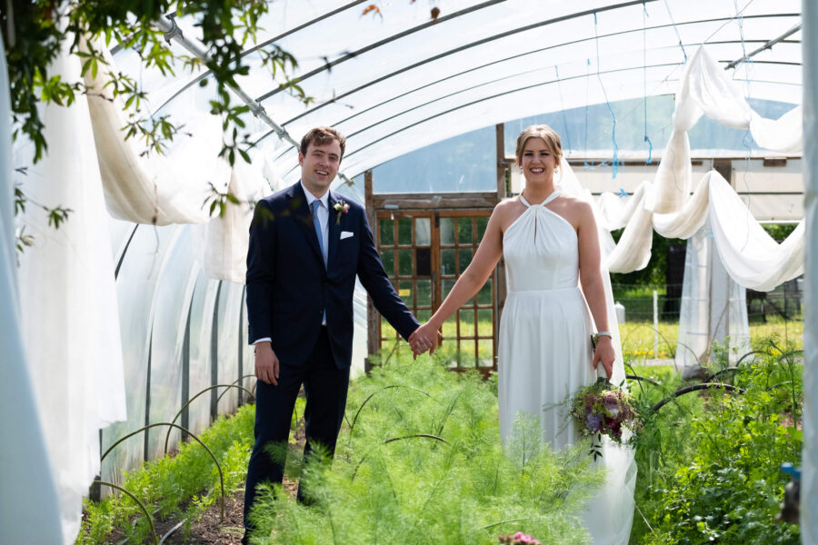 Bride and groom hand in hand in the vegetable tunnels of Cloughjordan house