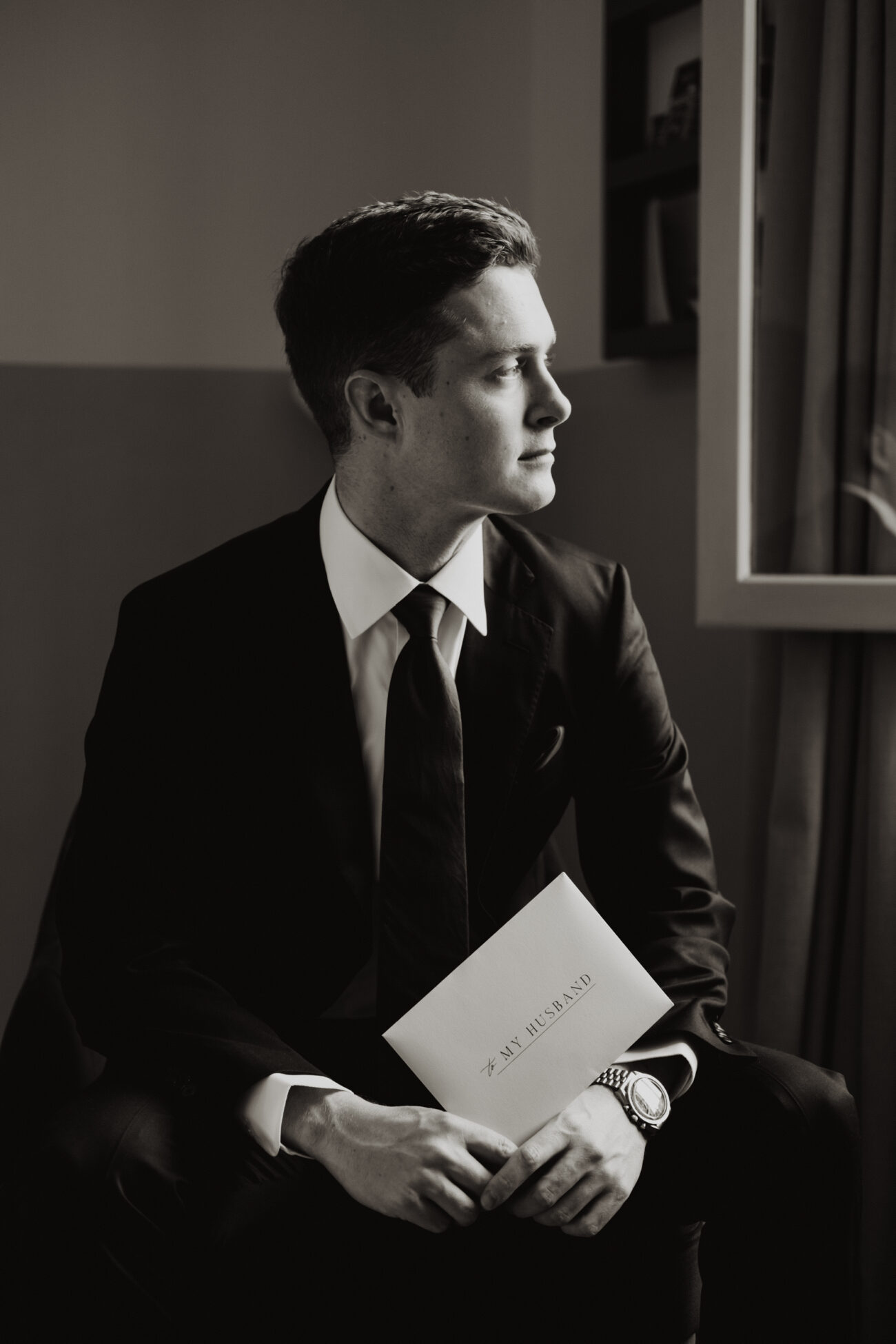 Groom sitting next to the window at The Clarence Hotel, elopement in Dublin City, wedding at The Clarence Hotel