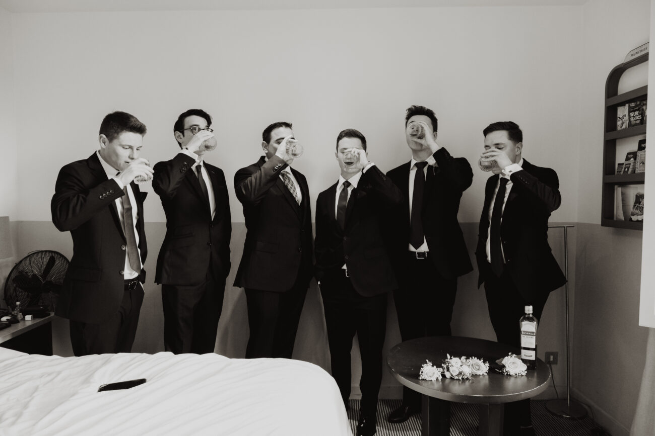 Groomsmen drinking whiskey toast before the ceremony at The Clarence Hotel, elopement in Dublin city, wedding at The Clarence hotel