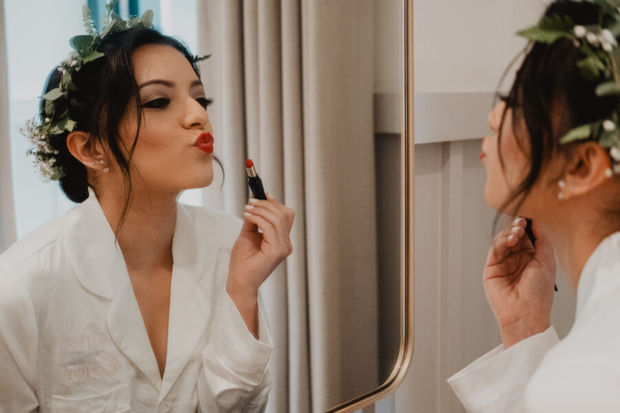 bride putting lipstick on during bridal prep at The Clarence Hotel, Elopement in Dublin City