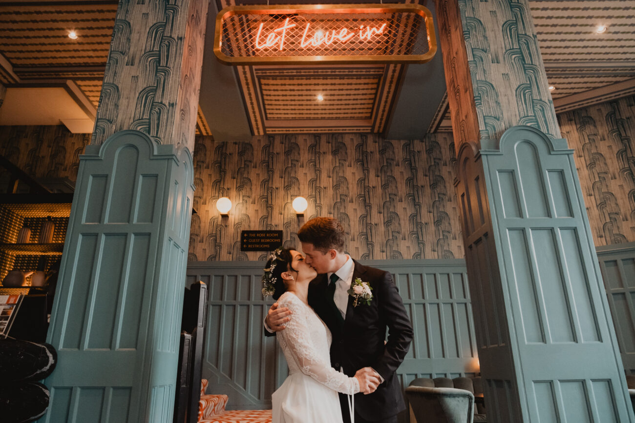 couple kissing under Let Love in sign at The Clarence Hotel