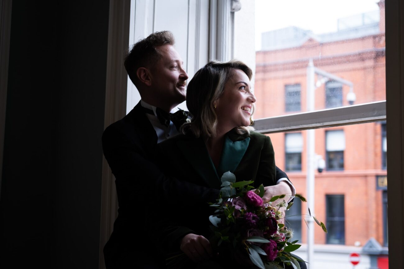 Bride and groom sitting in arms, looking out the window at no 5 South Leinster street at their wedding at The National Gallery of Ireland