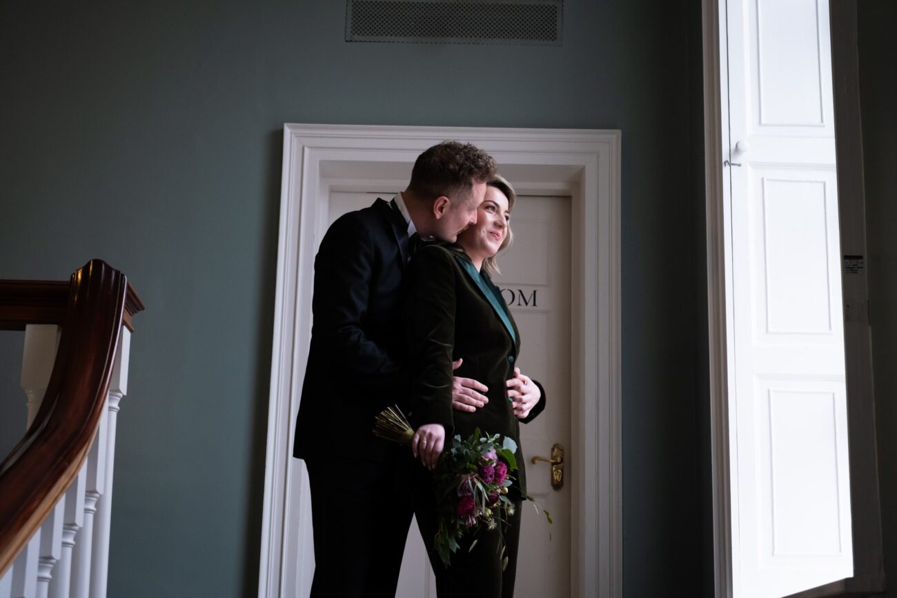 Bride and groom standing in arms, looking out the window at no 5 South Leinster street at their wedding at The National Gallery of Ireland