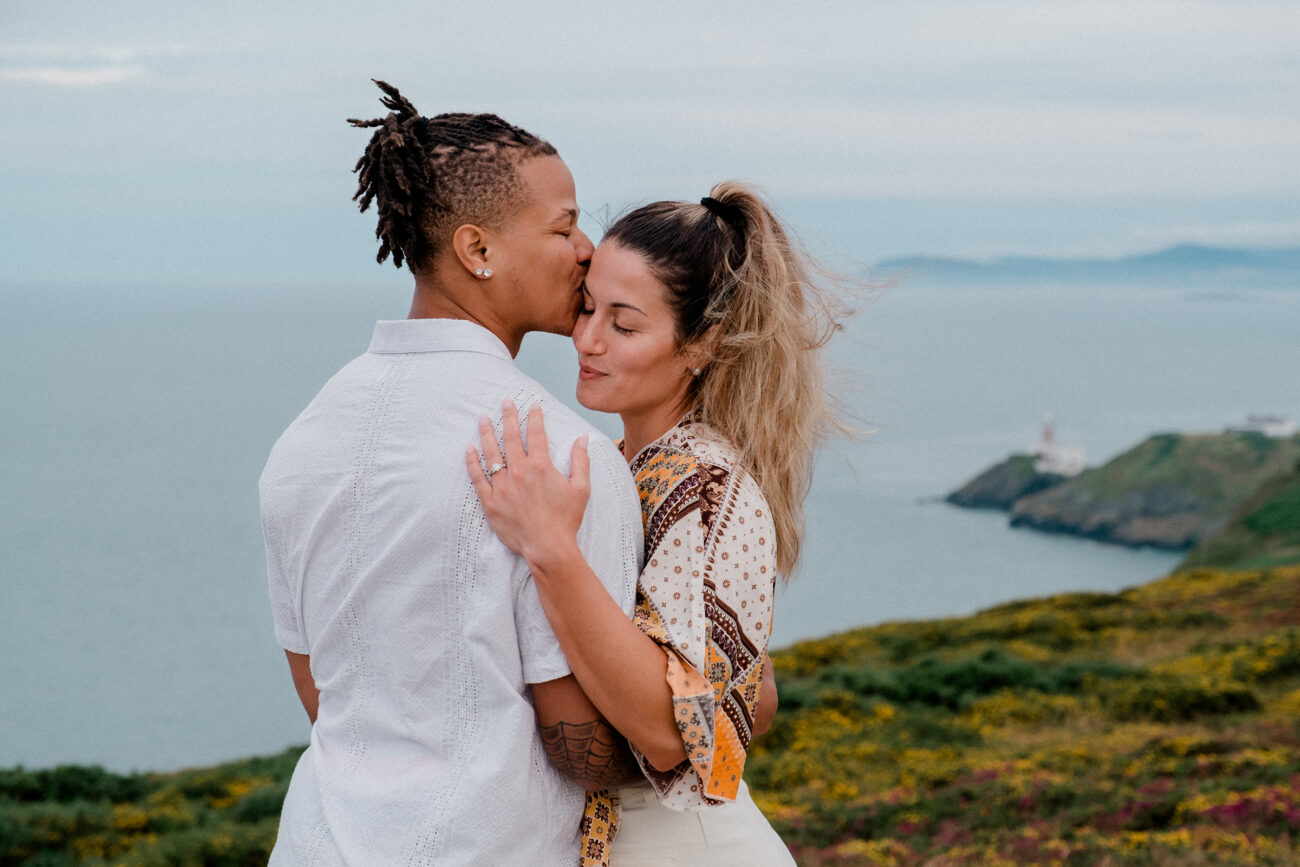 man kissing his partners head during a secret proposal engagement shoot at Howth Summit