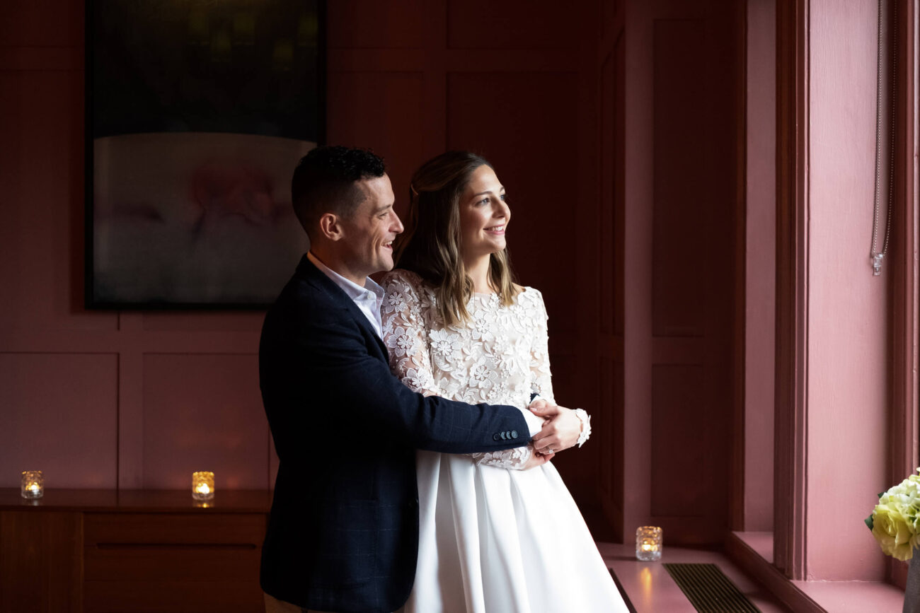 Bride and groom standing by the window in the Rose Room  at The Clarence Hotel