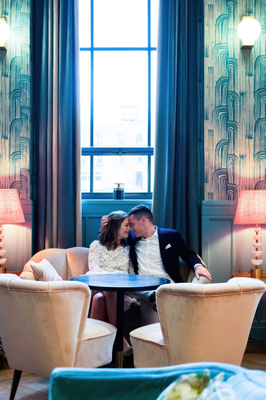 Bride and groom sitting in the main bar, heads together at The Clarence Hotel