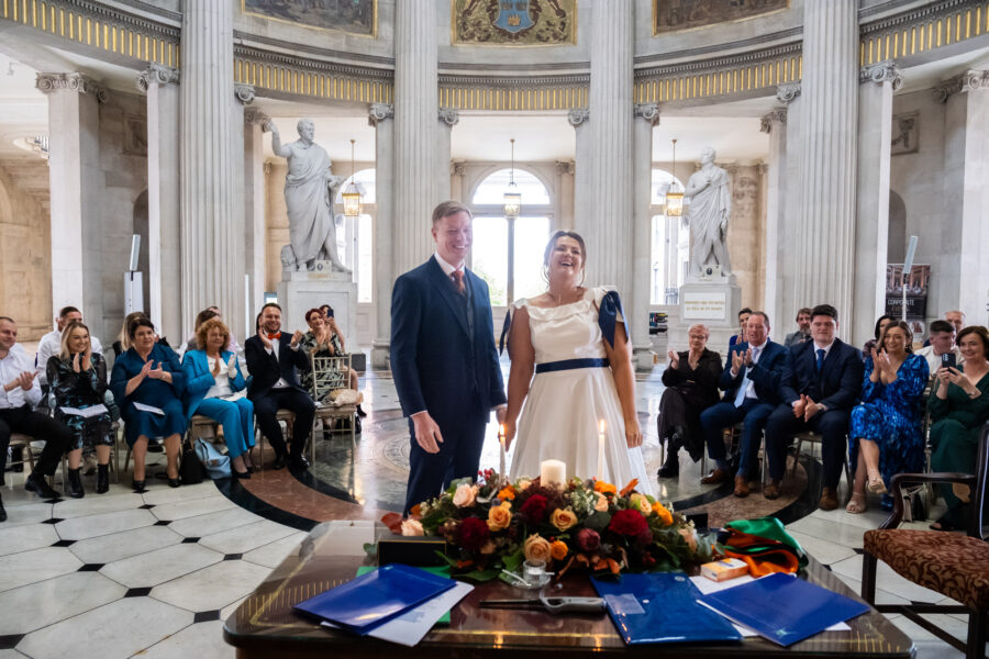 brdie and groom smiling with family in the background at Dublin City Hall