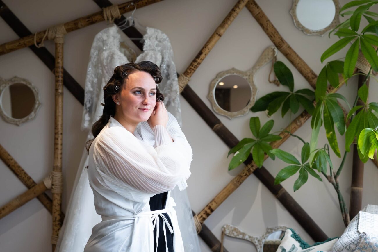 Bride fixing her earings and looking out the window at Ballymagarvey Village bridal prep