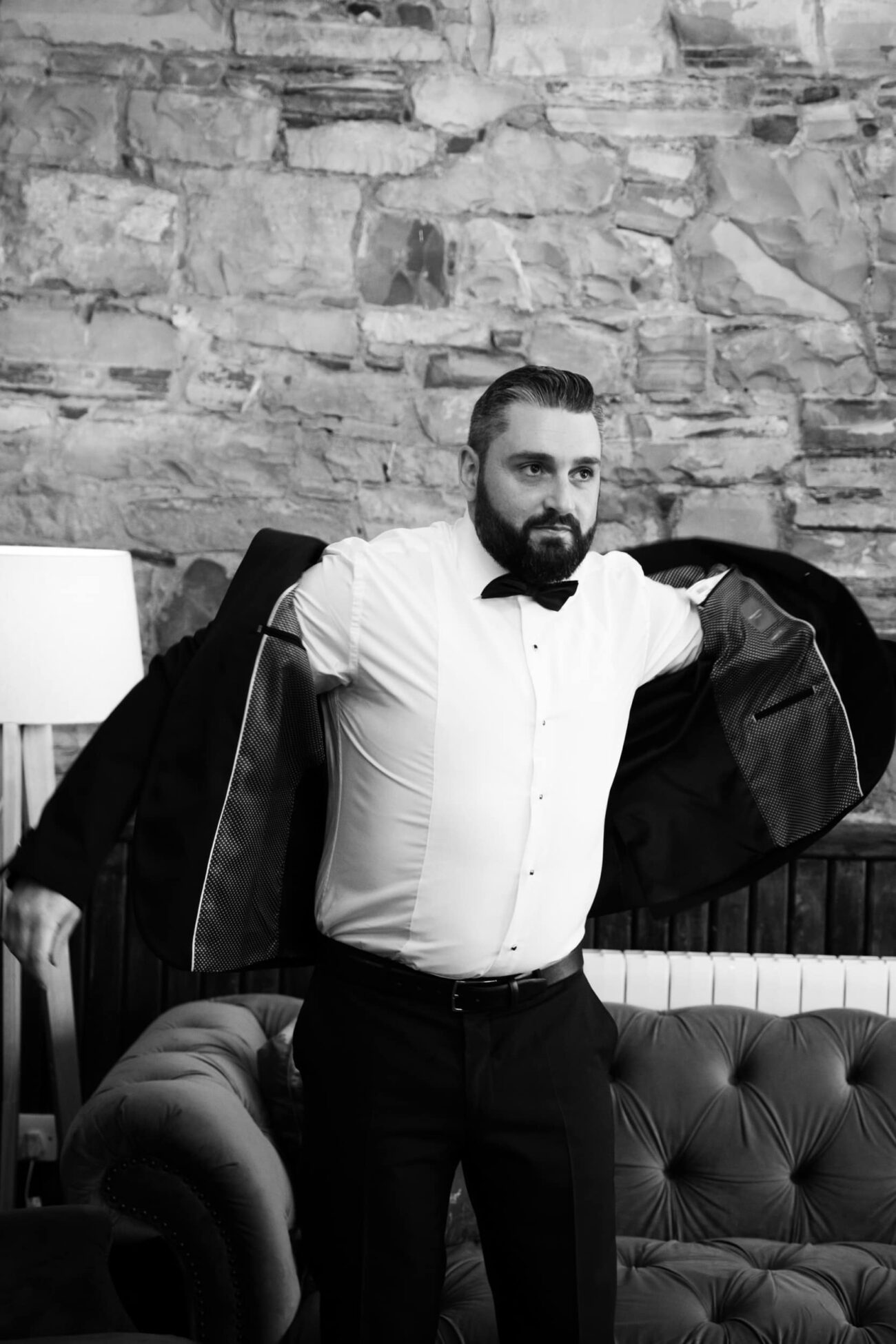 Groom putting on his jacket in the coach house at Ballymagarvey Village