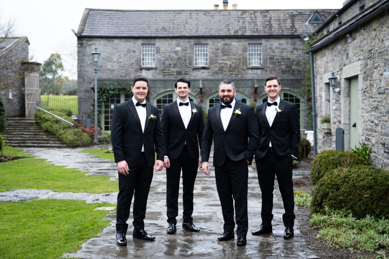 Groomsment standing outside the coach house at Ballymagarvey Village