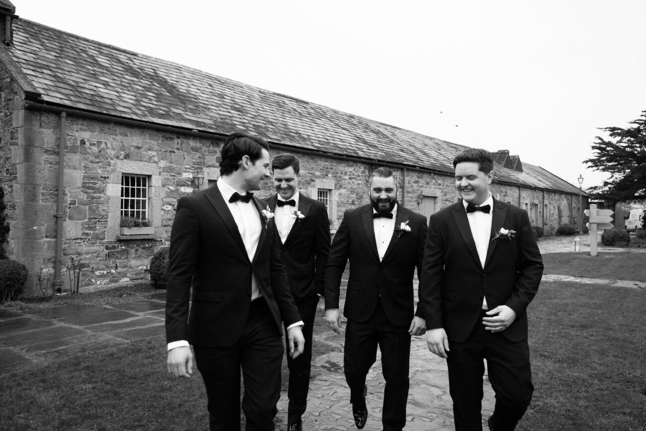 Groomsmen walking in the courtyard at Ballymagarvey Village