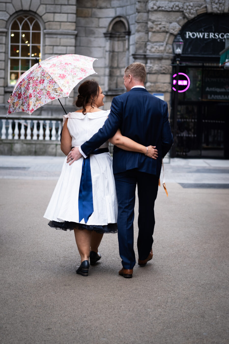 Bride and groom walking arm in arm down the streets of Dublin