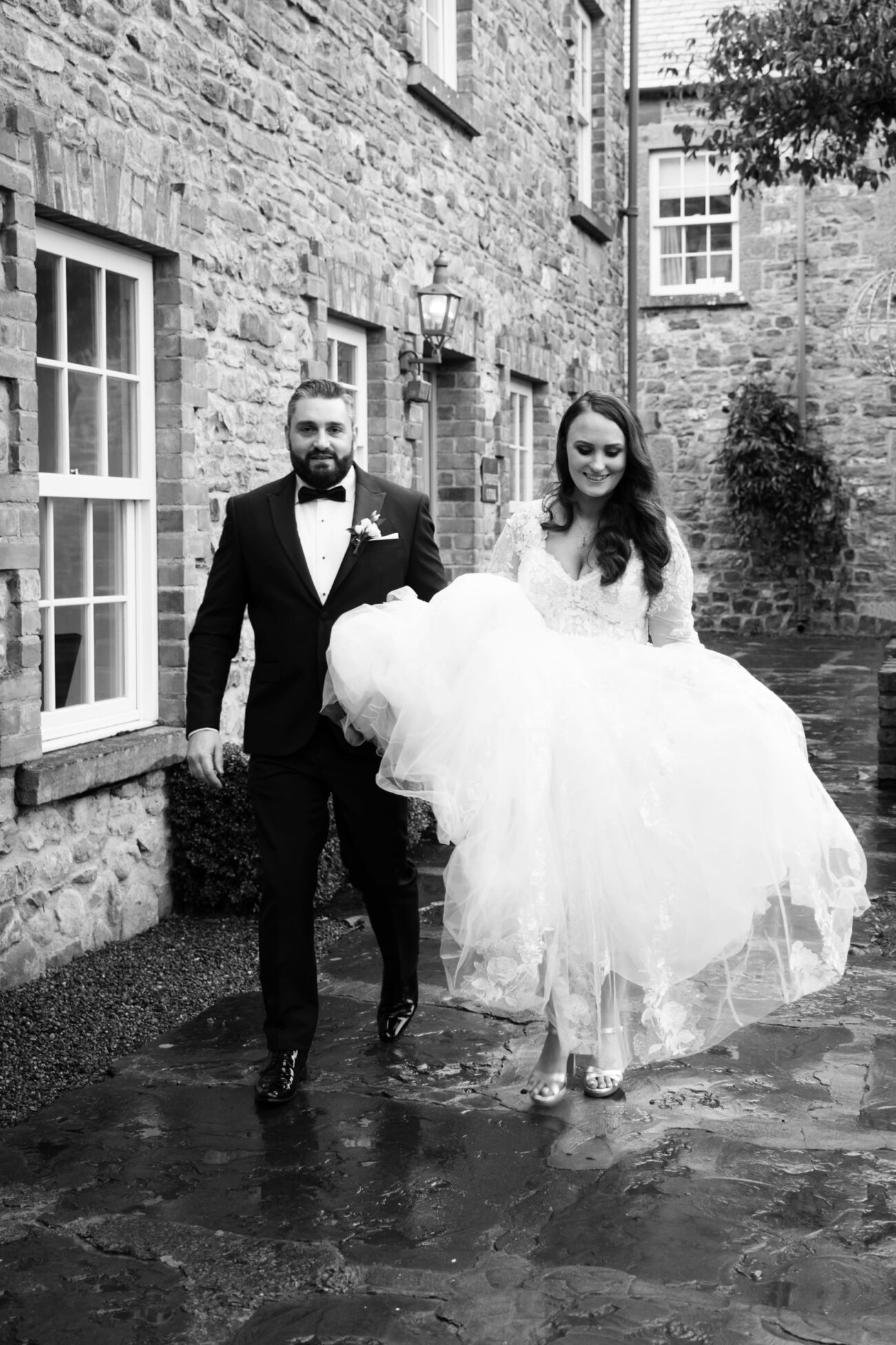 bride and groom walking through a rainy courtyard at Ballymagarvey Village