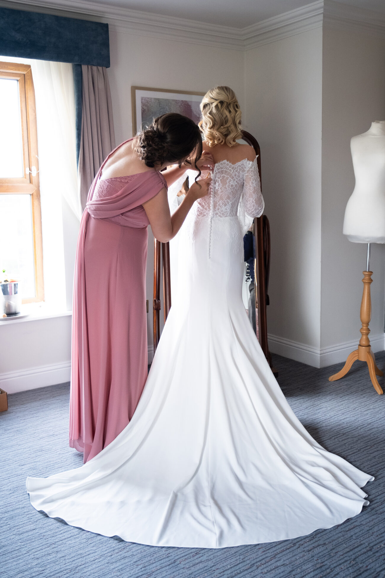 Maid of honour doing up the brides dress at Killashee Hotel