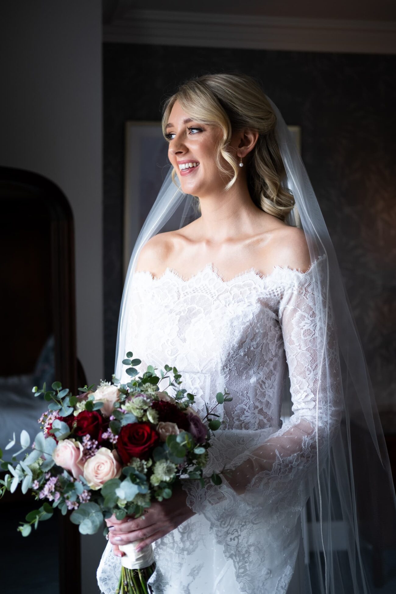 Bride holding flowers and looking out the window