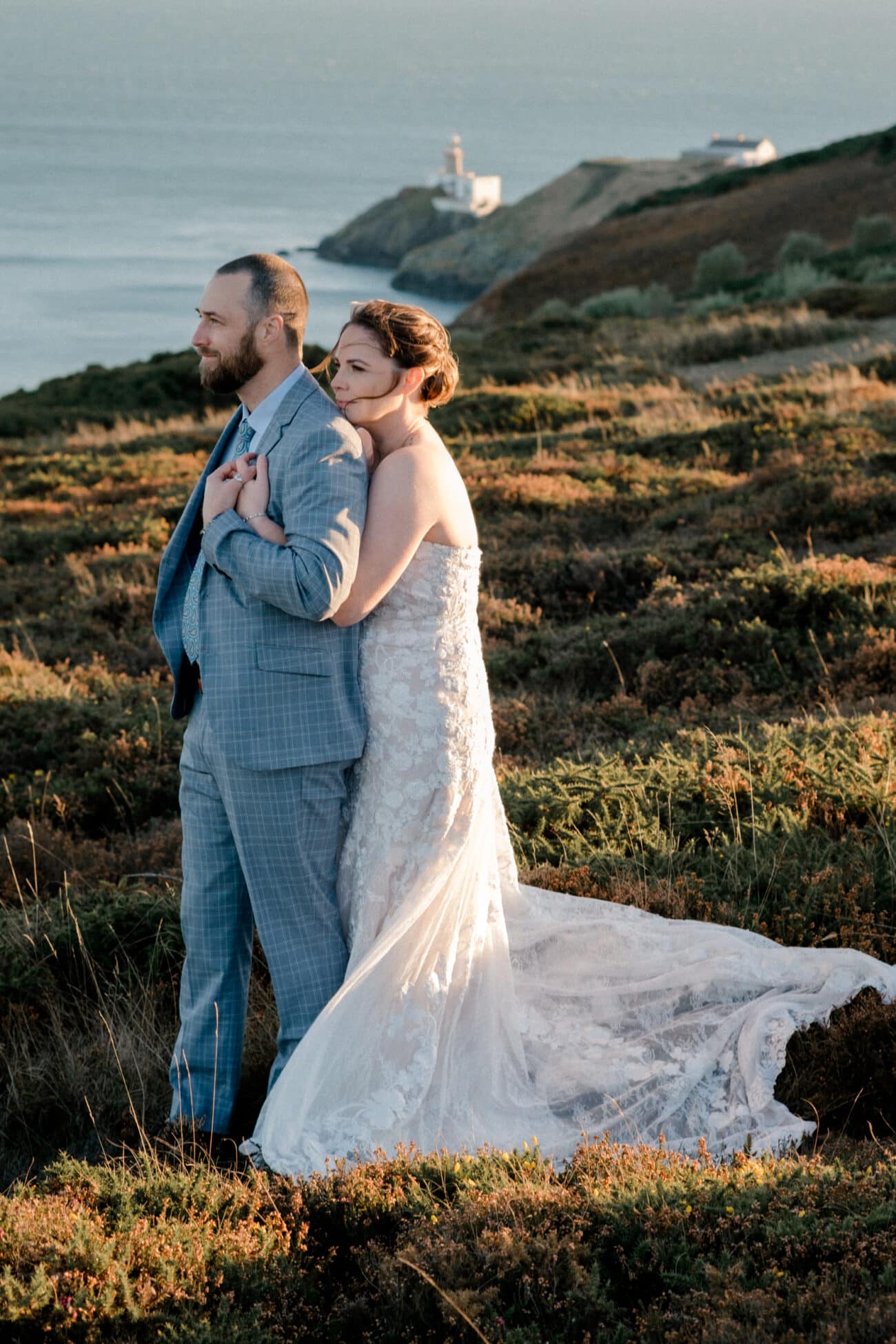 bride hugging her groom and looking into the distance on Howth Summit, vow renewal Howth Summit