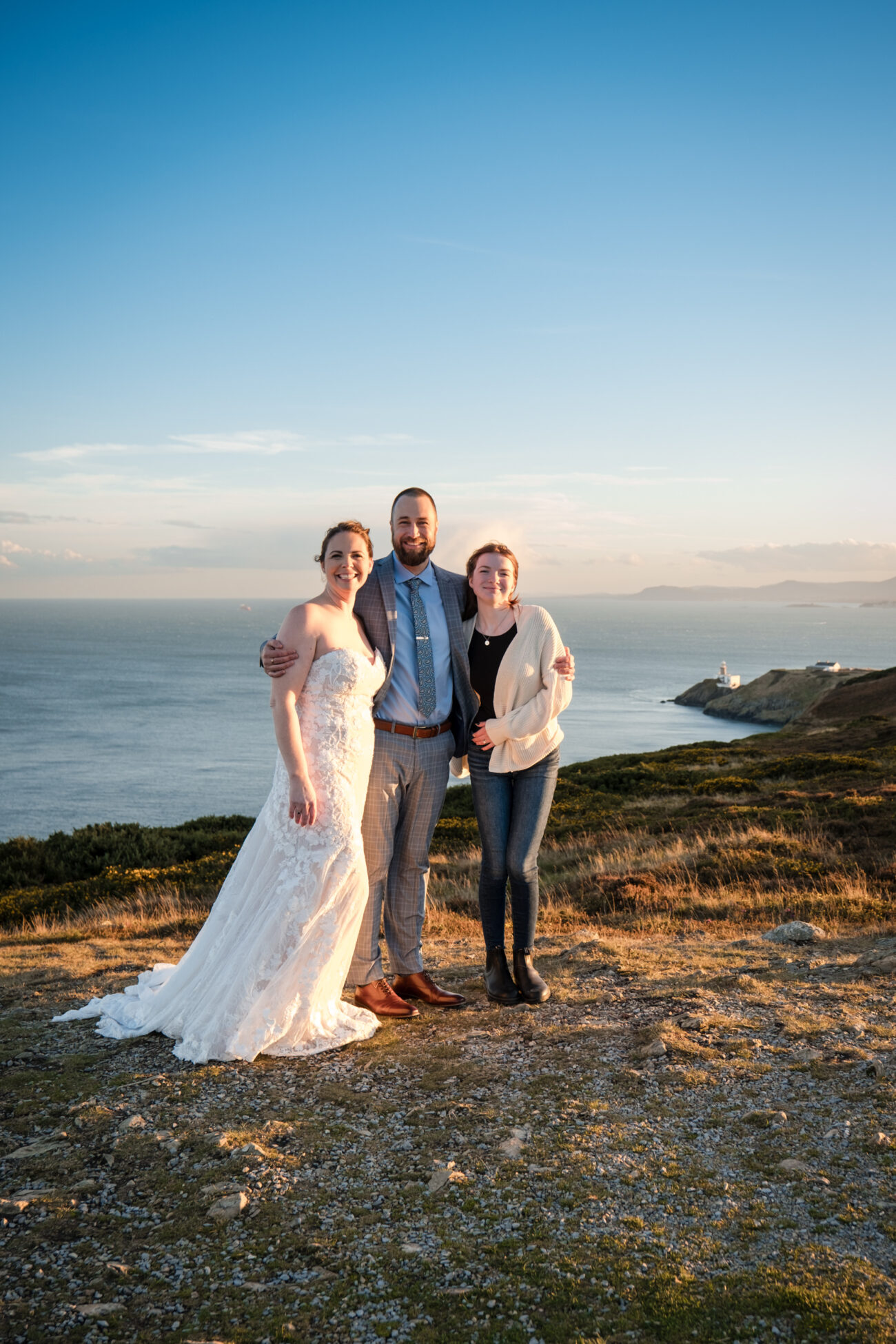 Bride and groom and daughter hugging at Cliffs of Howth