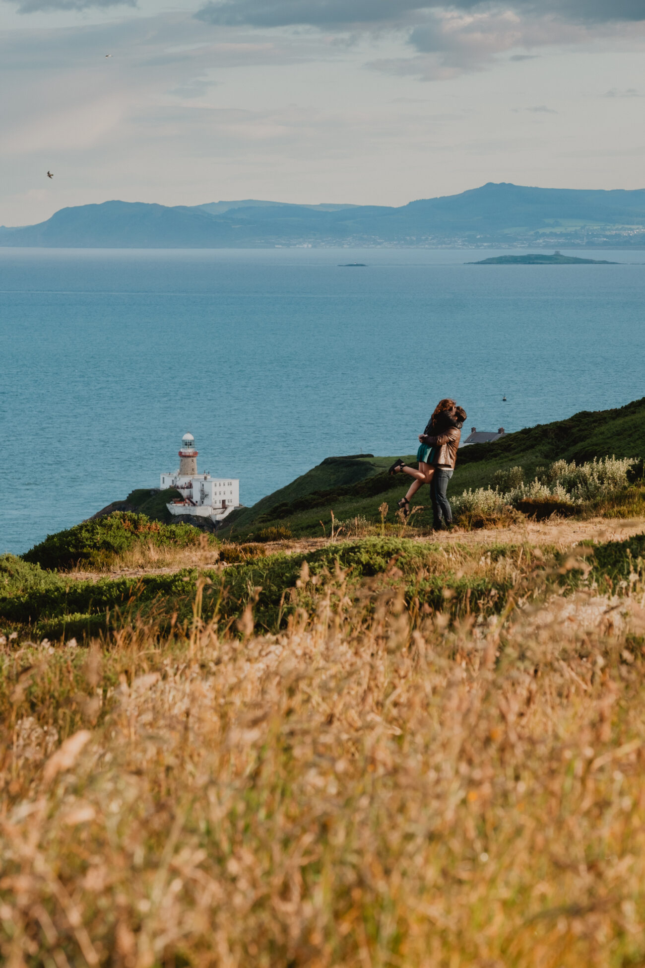 Engagement photoshoot in Howth Summit. Secret proposal on Cliffs of Howth, couple hugging