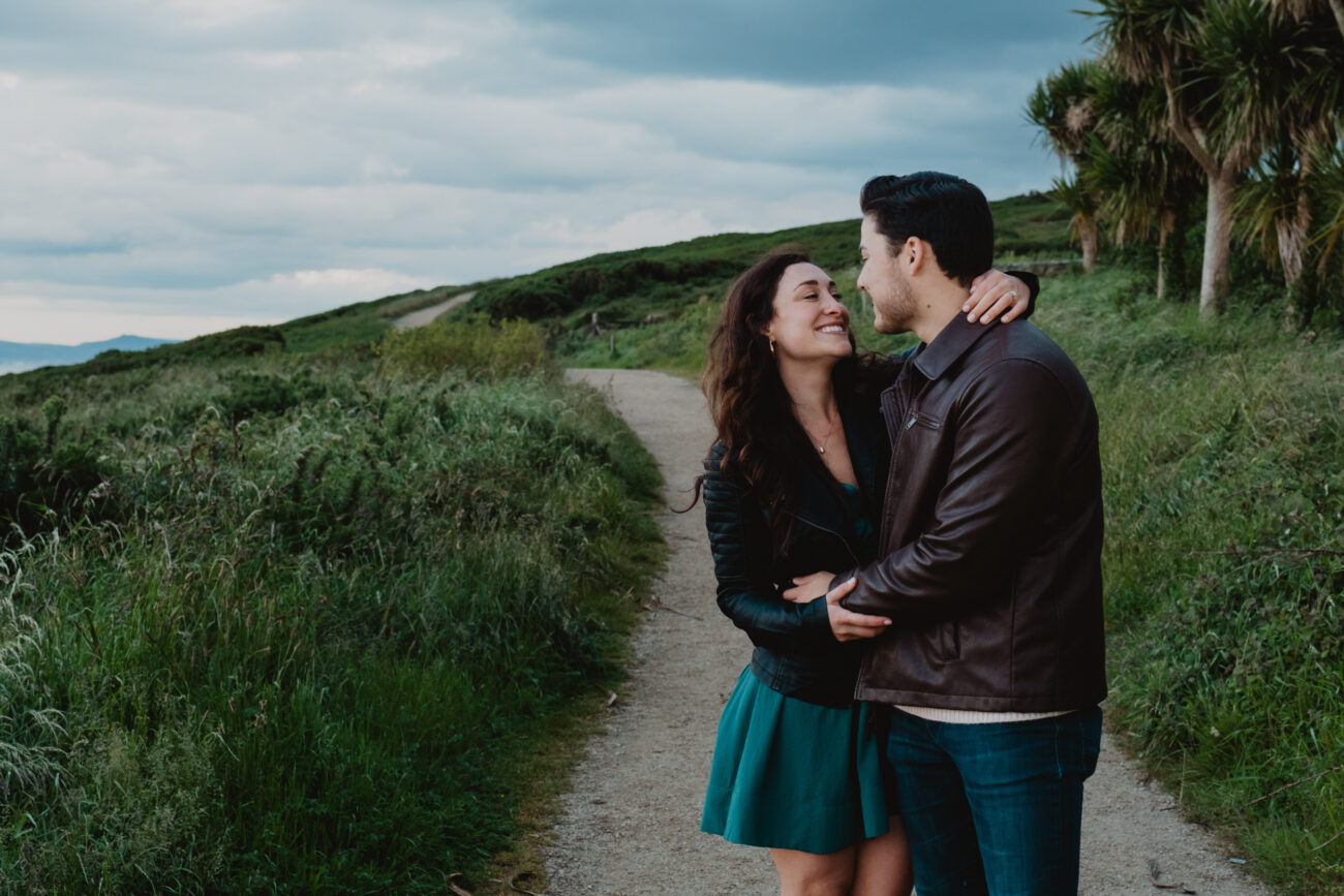 Couple hugging and looking at each other on Howth Head. Secret proposal on Cliffs of Howth