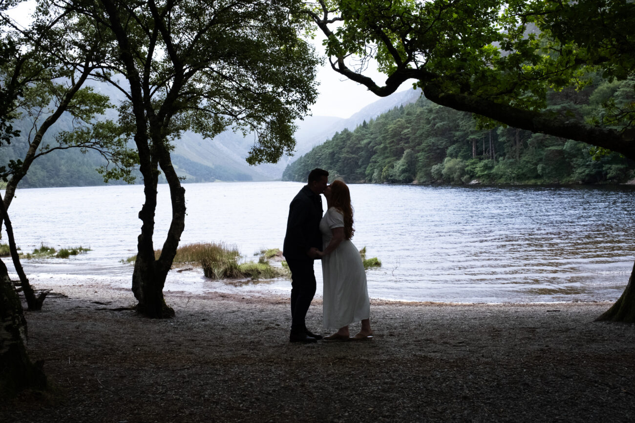 Couple kissing under the trees at Glendalough