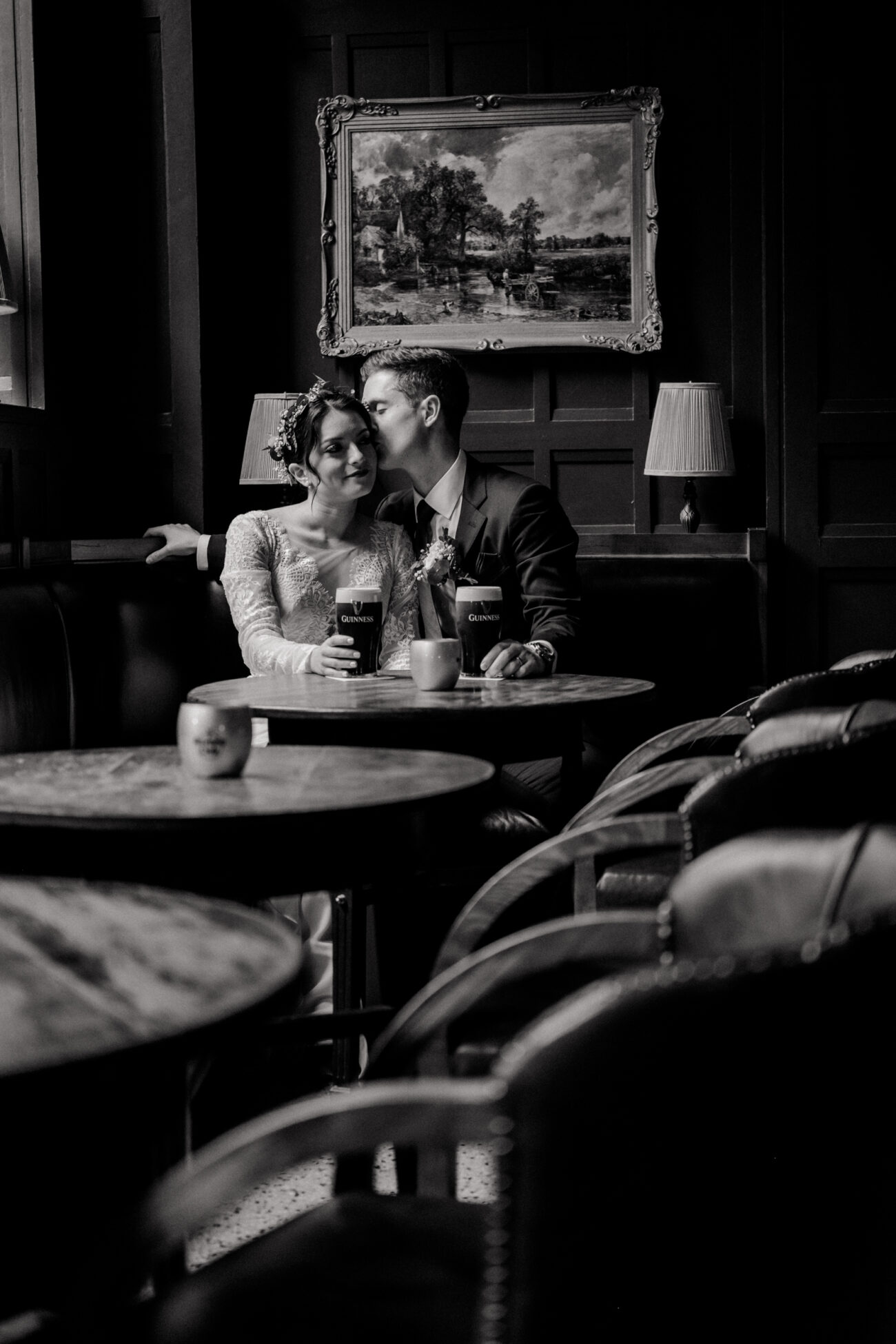 groom kissing brides cheek in the pub in The Clarence Hotel, drink Guinness