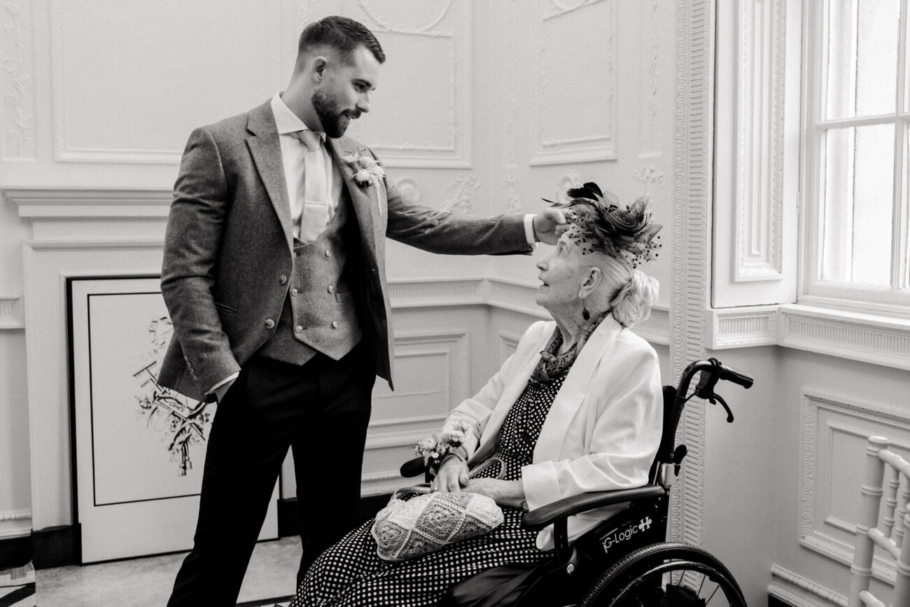 groom fixing his Granny's hair during ceremony at a wedding. Candid wedding photography