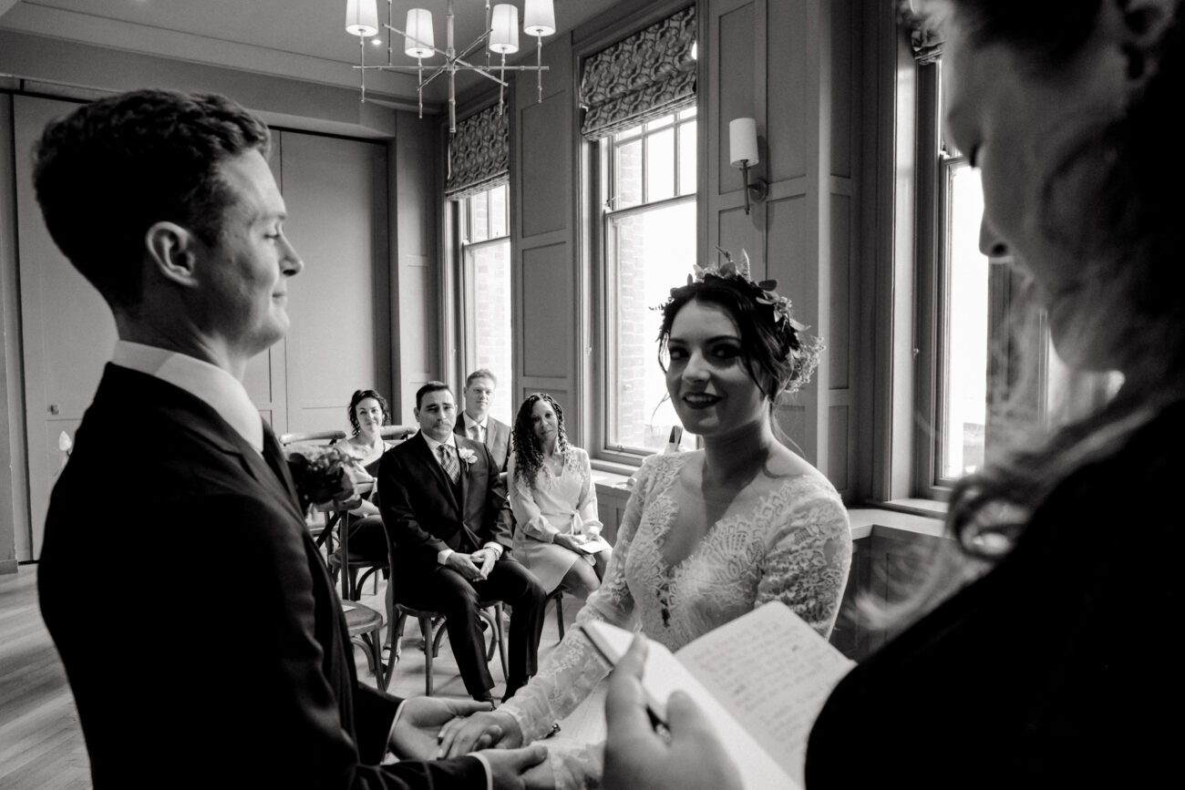 bride and groom saying theor vows as the brides father looks at them