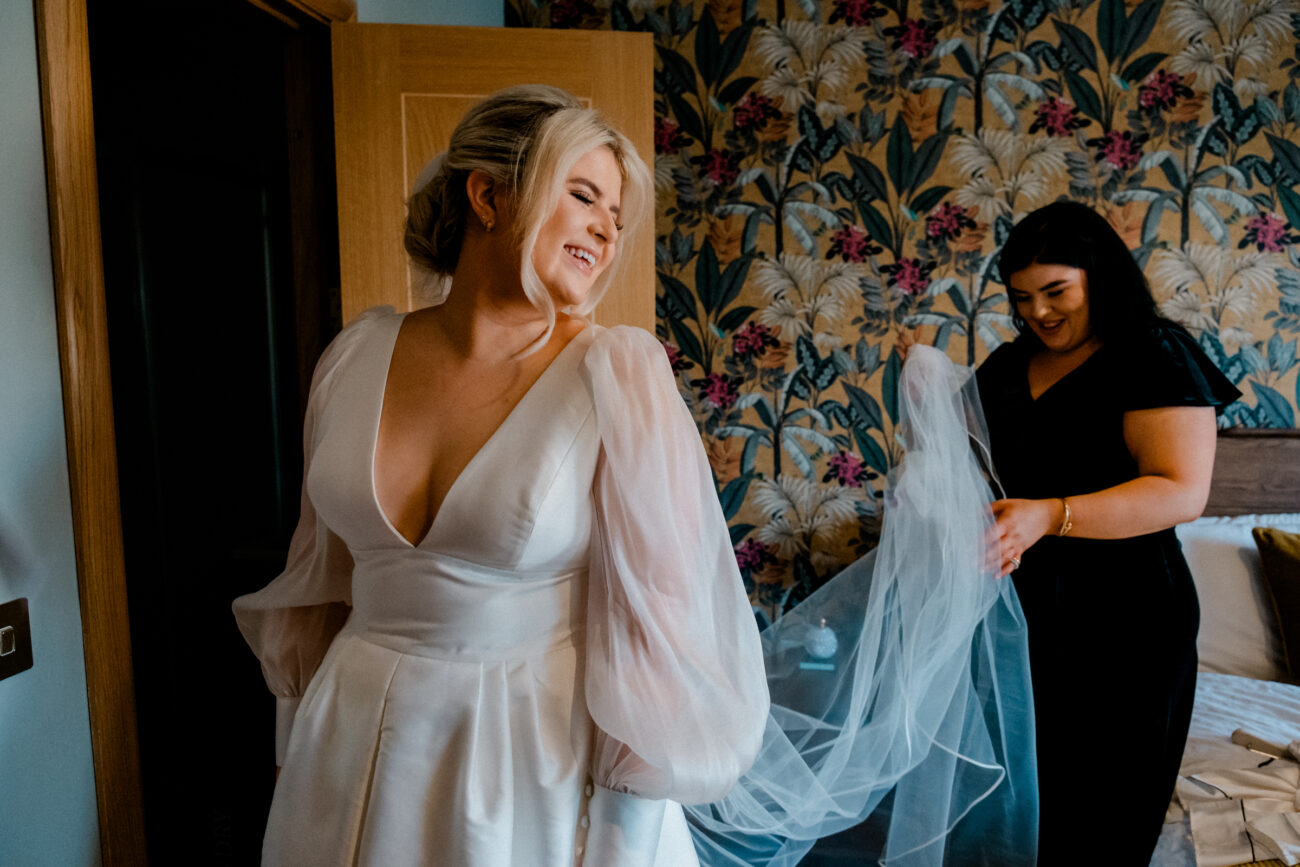 bridesmaid adjusting veil in bedroom, candid wedding photography